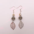 Smoky crystal and silver filigree leaf dangle earrings on white background