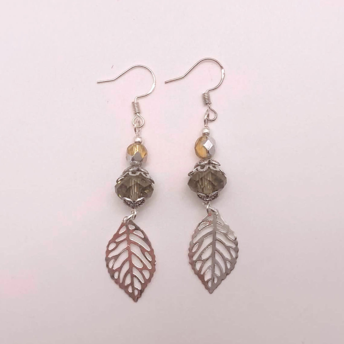 Smoky crystal and silver filigree leaf dangle earrings on white background