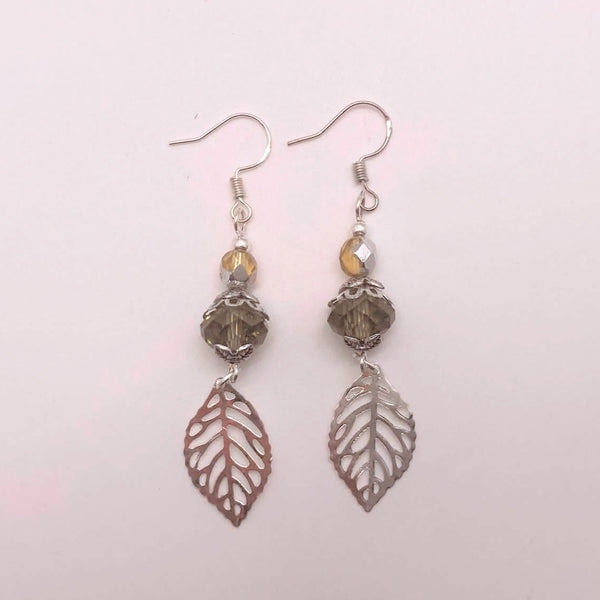 Smoky crystal and silver filigree leaf dangle earrings on white background