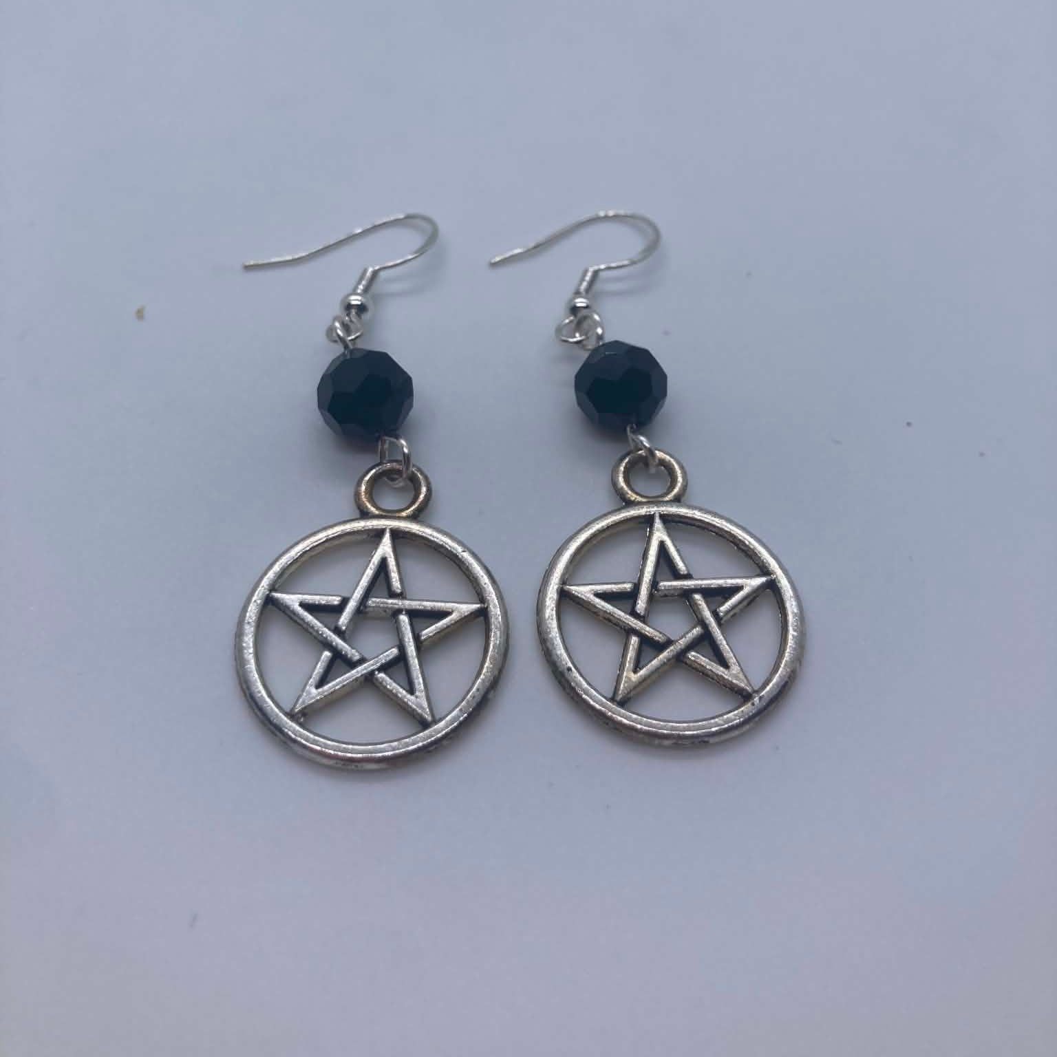 Pentacle earrings with black beads on a light gray background