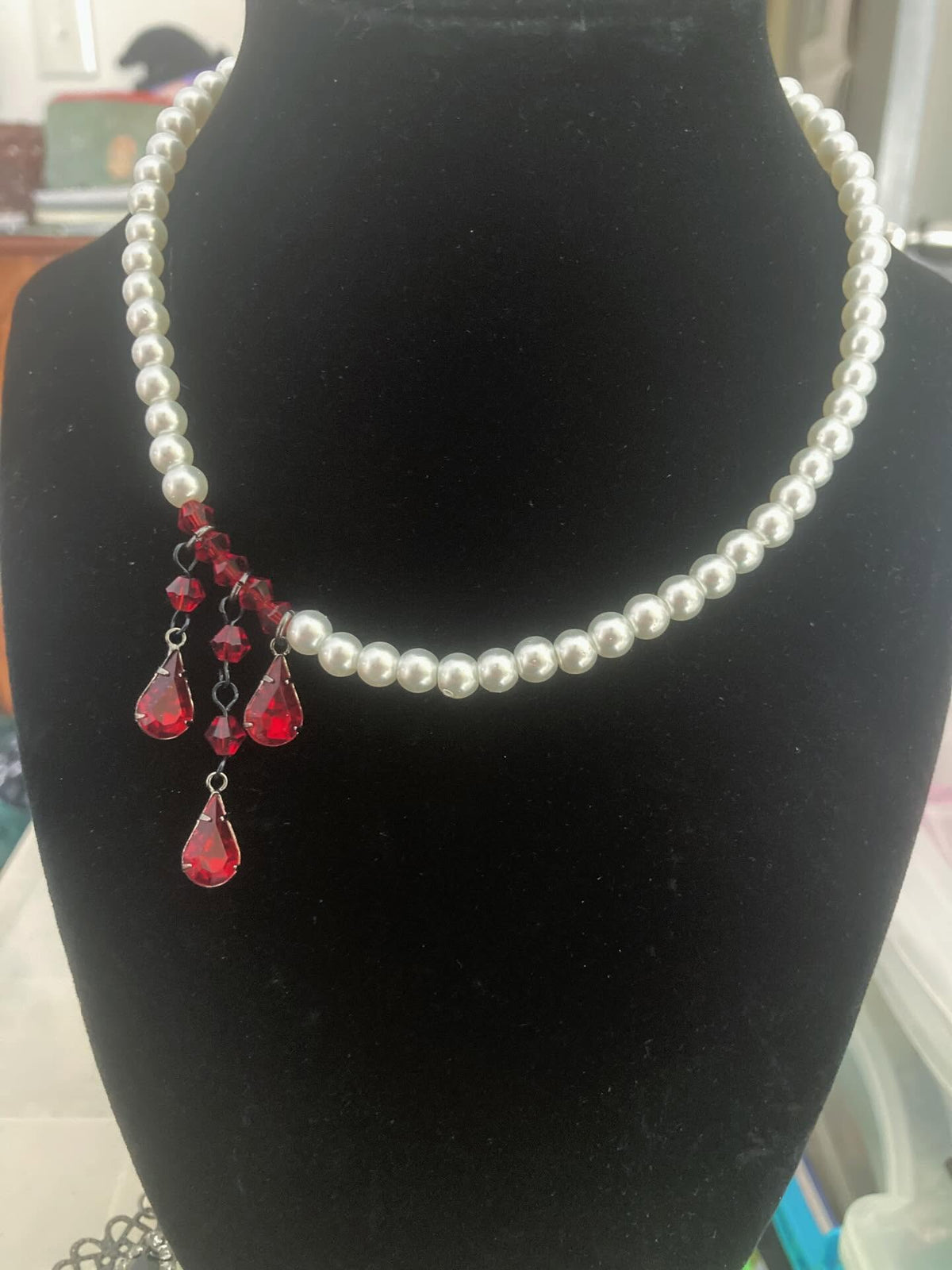 Vampire Pearls glass pearl necklace with asymmetric dark red crystal drops on display