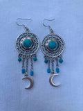 Pair of silver earrings with turquoise stones on a light blue background