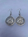 Pair of silver earrings with intricate designs on a light blue background