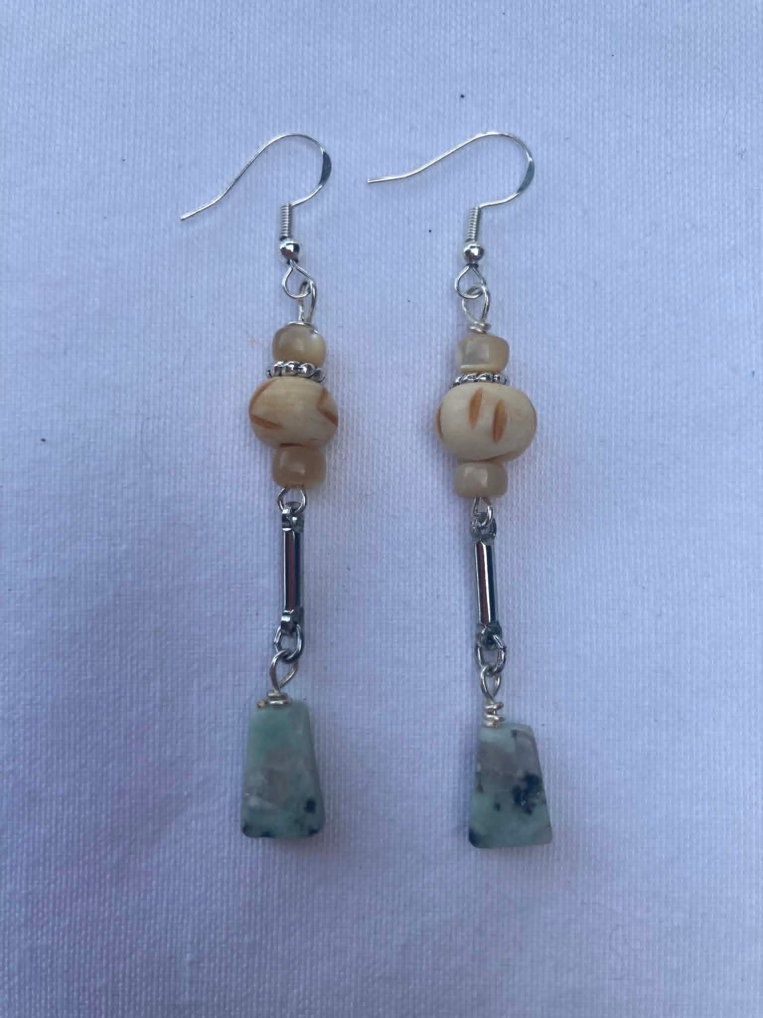 Pair of beaded earrings on a light blue fabric background