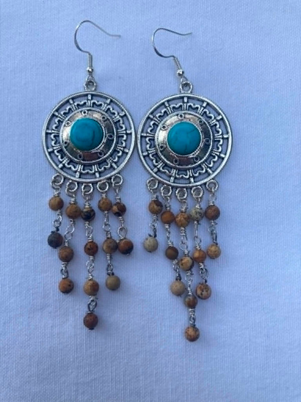 Pair of silver earrings with turquoise stones and picture jasper beads on a light blue background